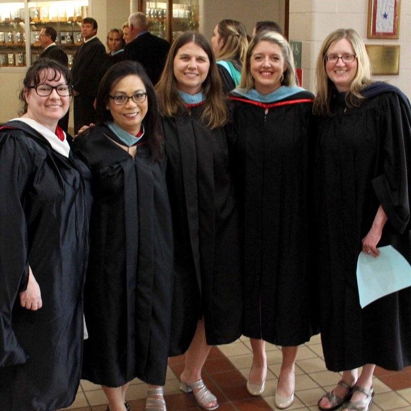 people smiling and wearing graduation cloaks